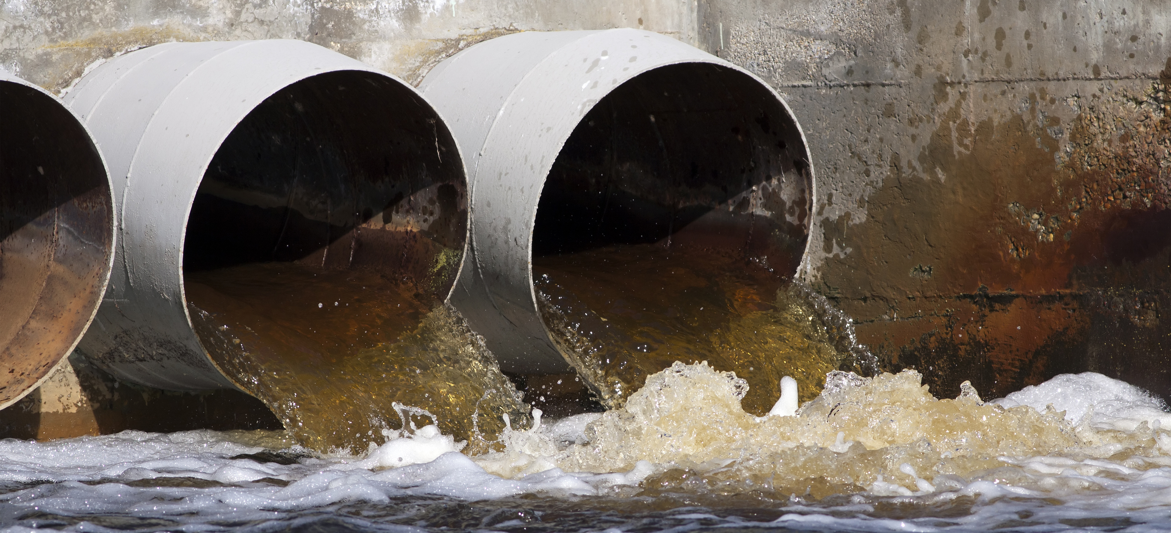 Toxic water flowing out of sewer drains into a river