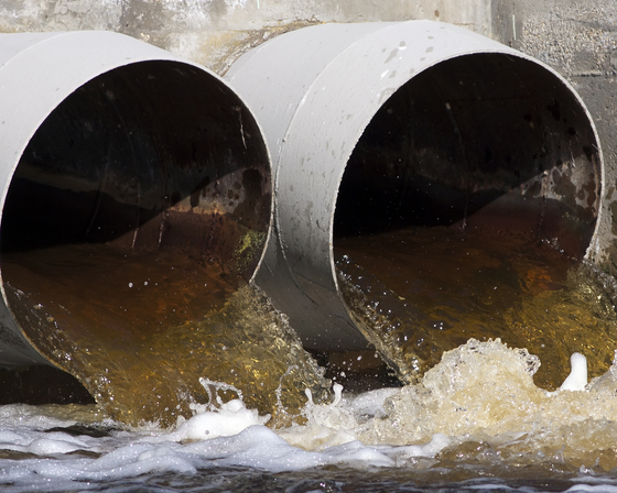 Toxic water flowing out of sewer drains into a river