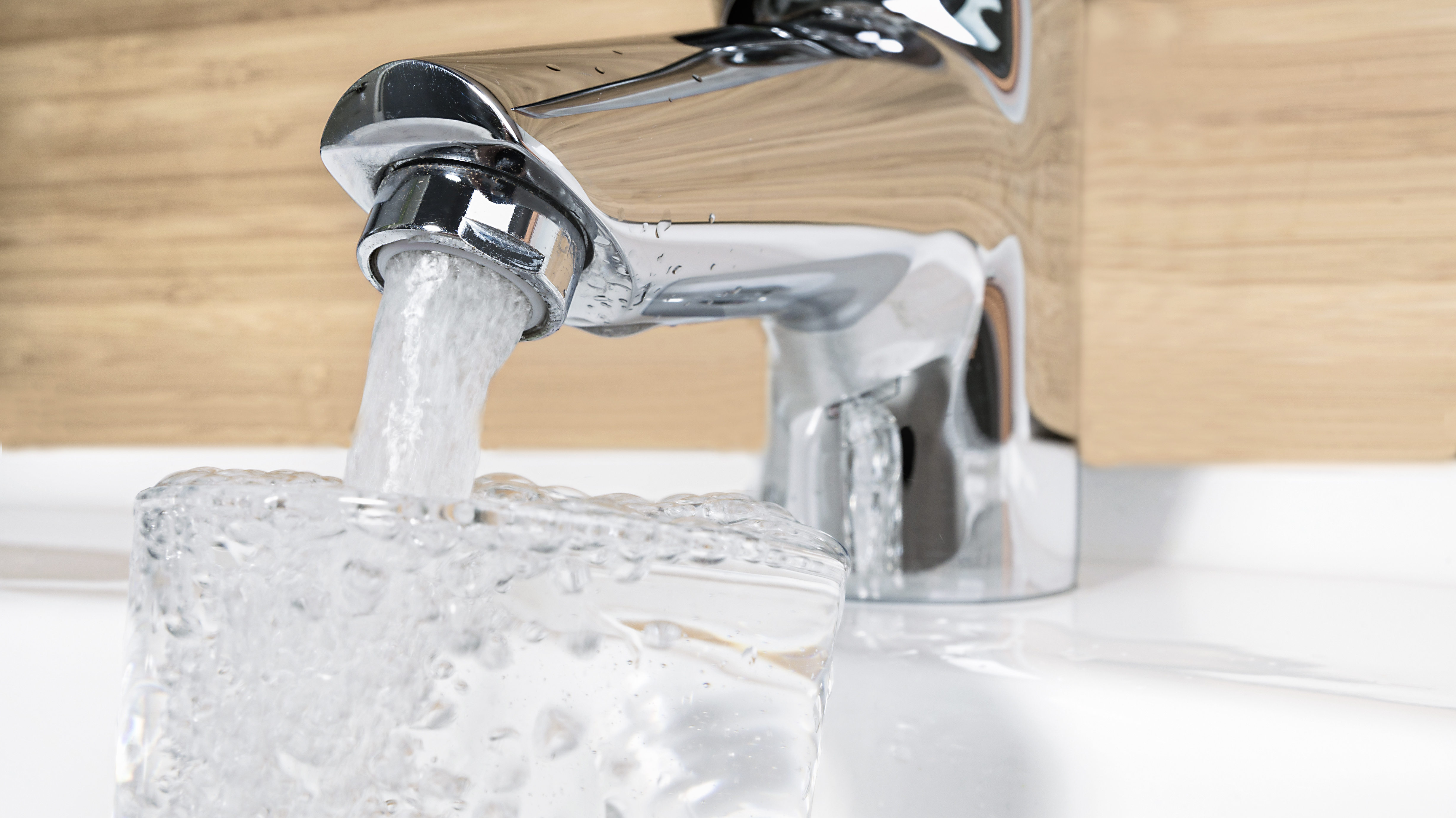Water flowing into a glass from a water faucet.