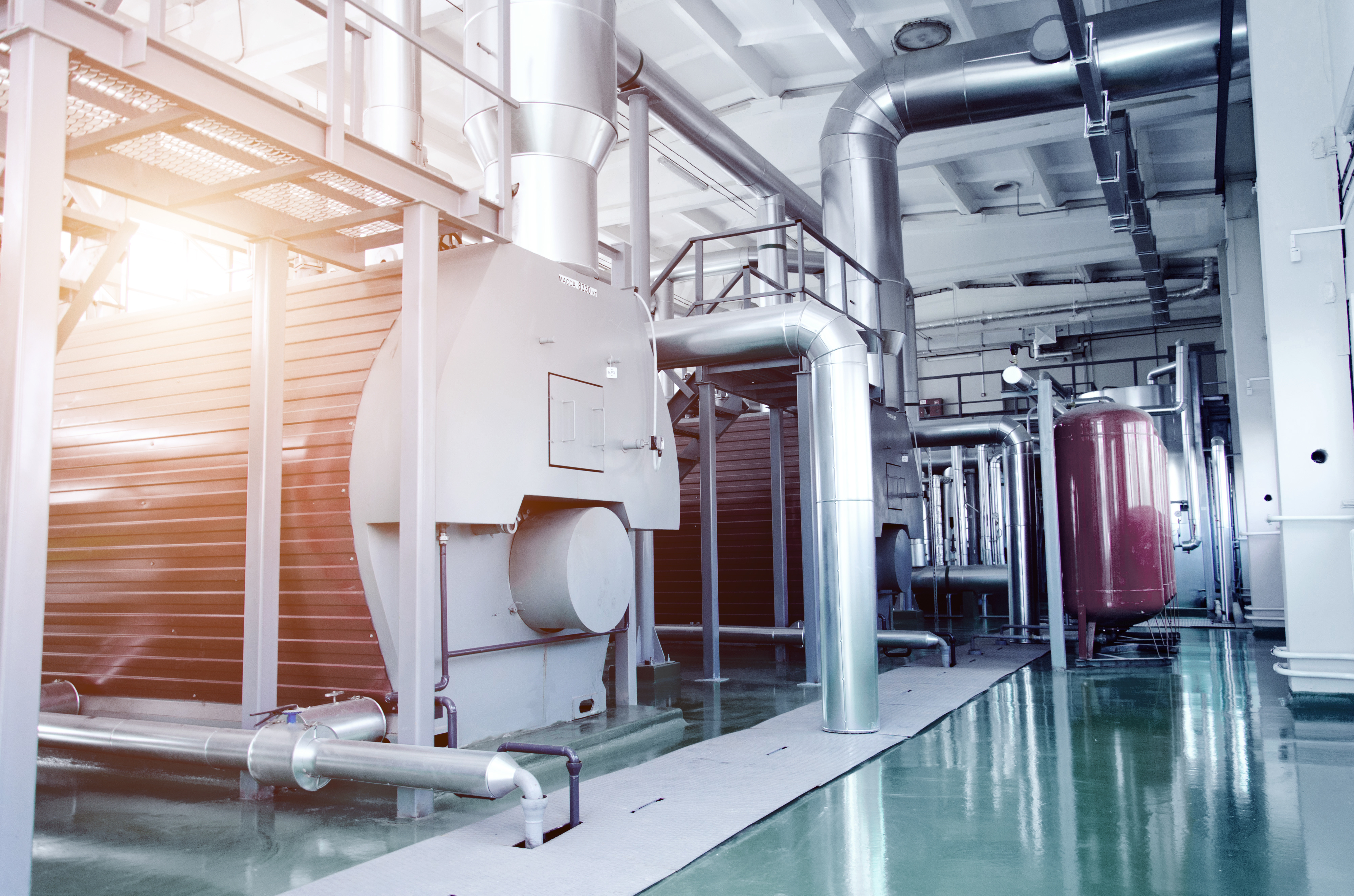 The interior of a modern industrial gas boiler room. Pipelines, water pumps, valves, manometers.