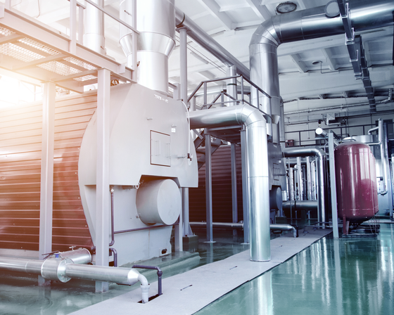 The interior of a modern industrial gas boiler room. Pipelines, water pumps, valves, manometers.